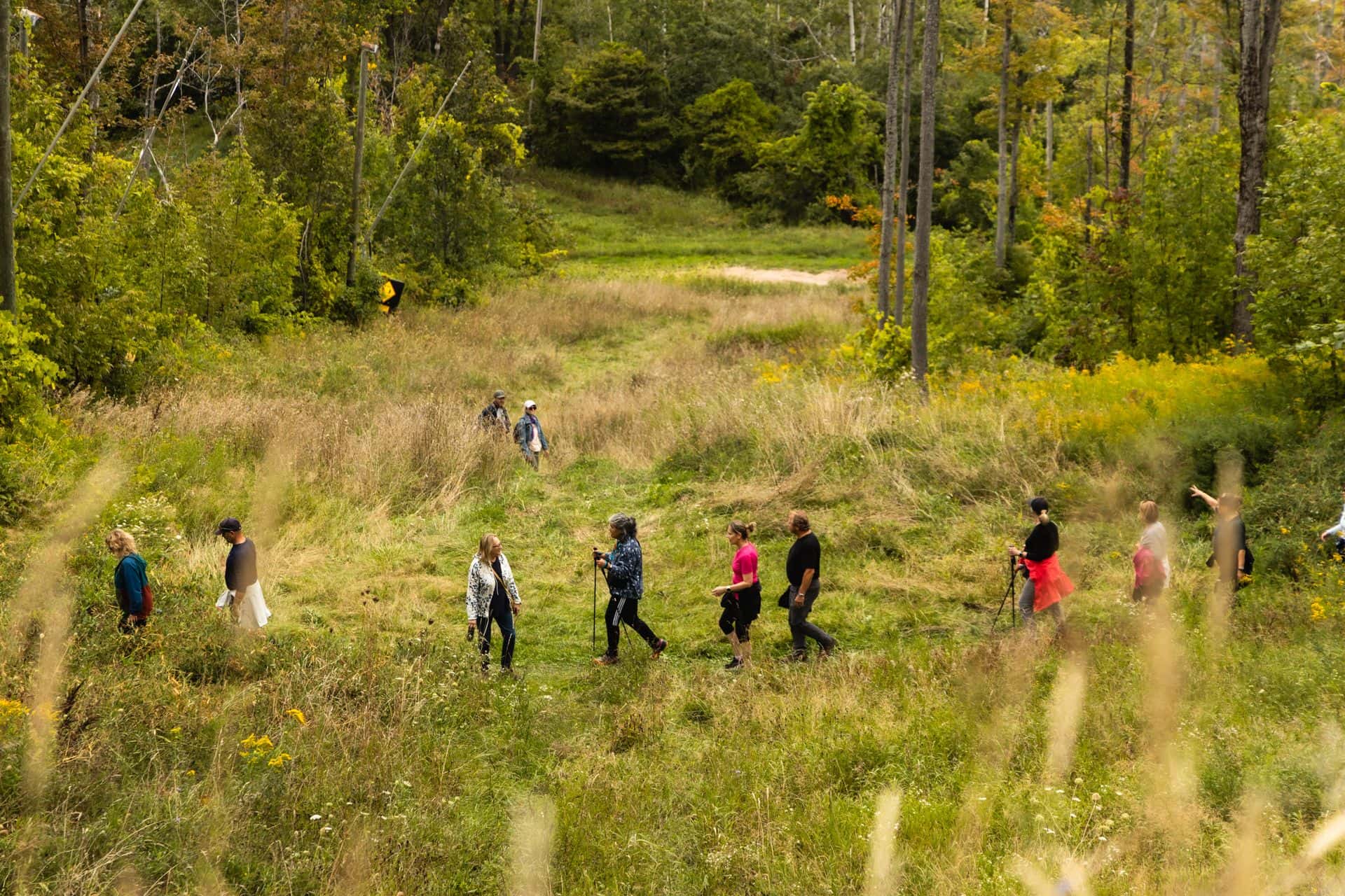 A zoomed out shot of hikers walking along an open area of the Village Way trail.