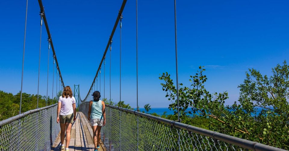 Two friends walk across the iconic suspension bridge at Scenic Caves Nature Adventures, adjacent to 168体彩网中国幸运飞开艇官网查询-幸运168体彩官网结果直播-中国168福彩飞艇记录号码查阅历史 Resort
